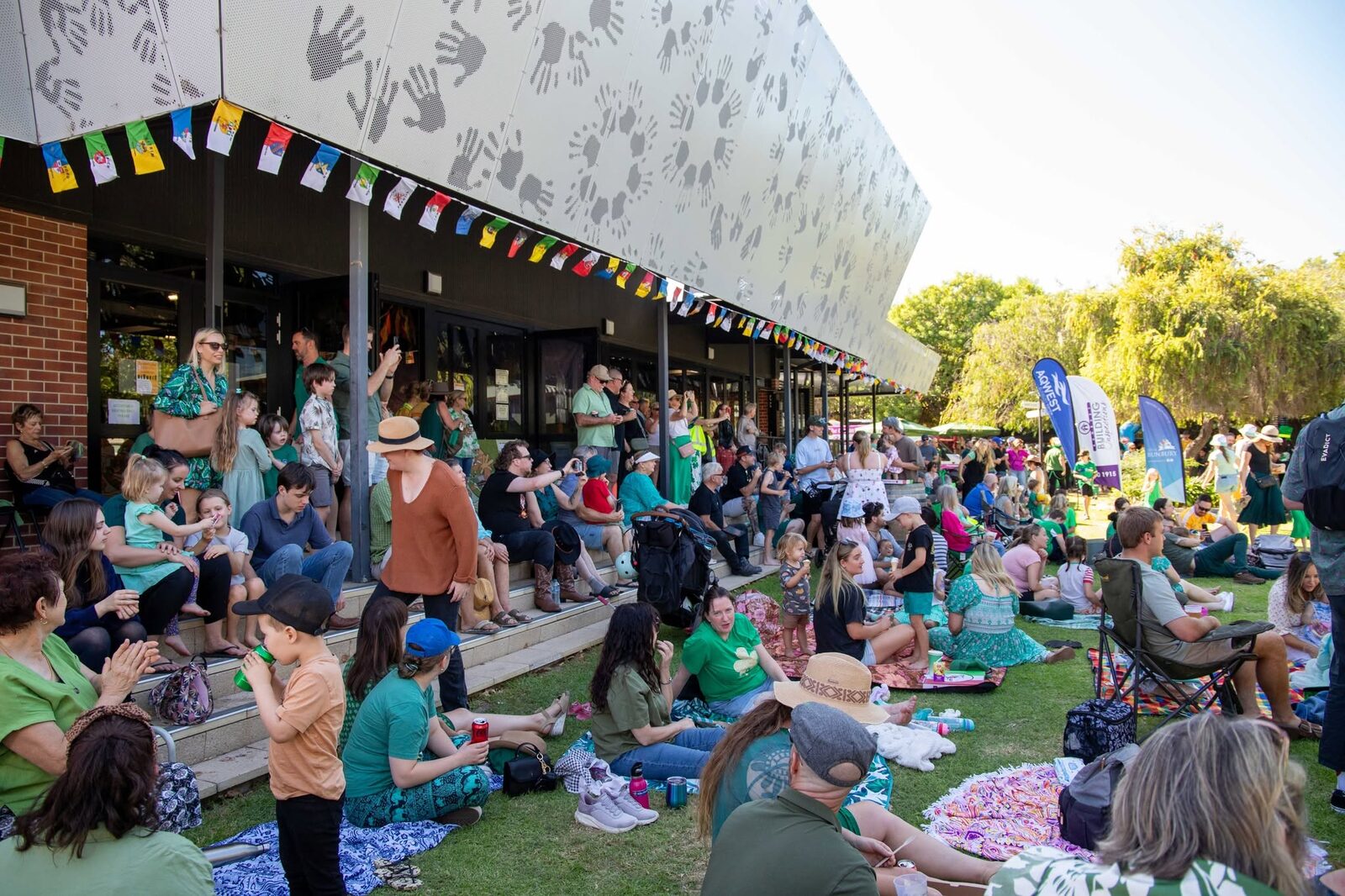 Crowds sitting along a building under bunting at the festival