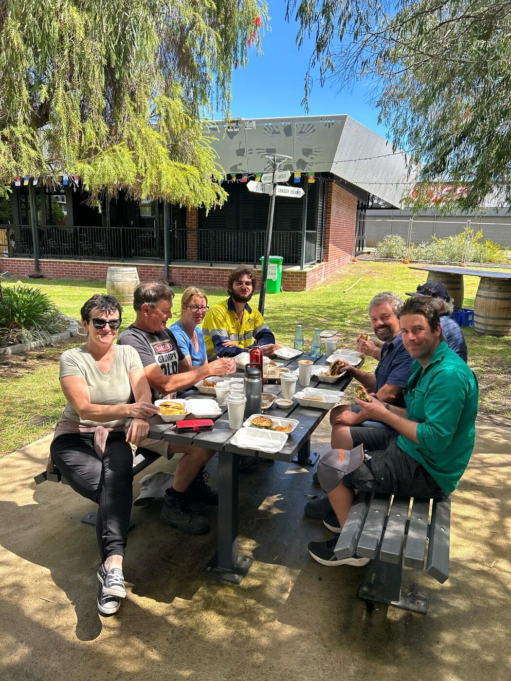 Volunteers at a picnic table under bunting, sharing a meal