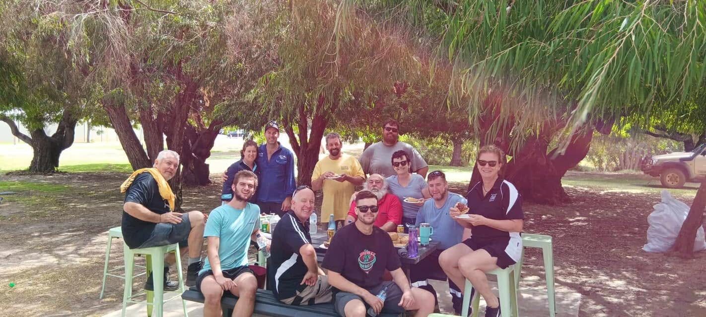 Volunteers sitting together under trees during the 2024 setup