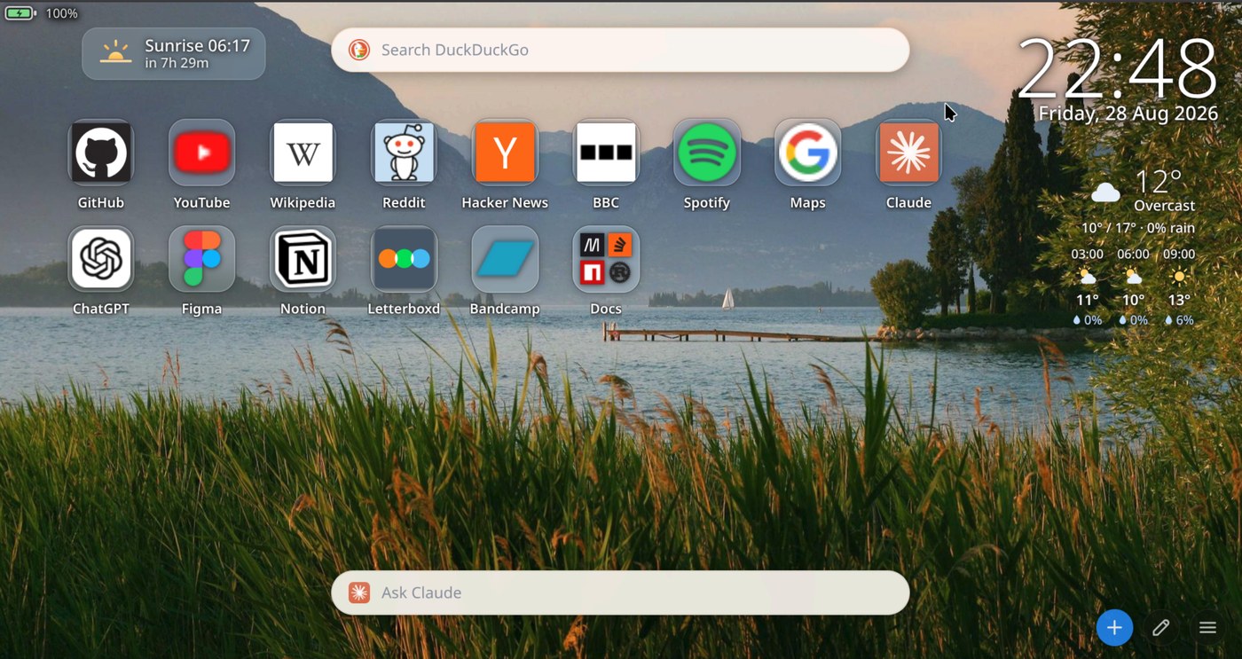 The new tab page: a grid of app tiles with real site icons — GitHub, YouTube, Wikipedia, Reddit, Hacker News, BBC, Spotify, Maps, Claude, ChatGPT, Figma, Notion, Letterboxd, Bandcamp and a Docs folder — over a lake wallpaper. A search bar sits at the top, a clock and weather at the right, a sunrise countdown at the left, and an Ask Claude bar along the bottom.